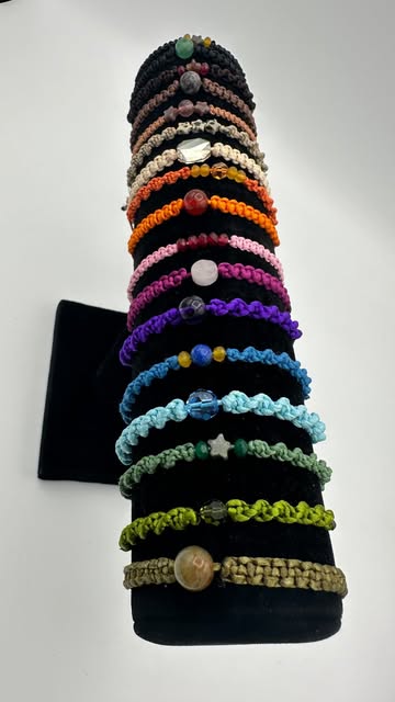 Tour de bracelets macramé multicolores sur un présentoir noir