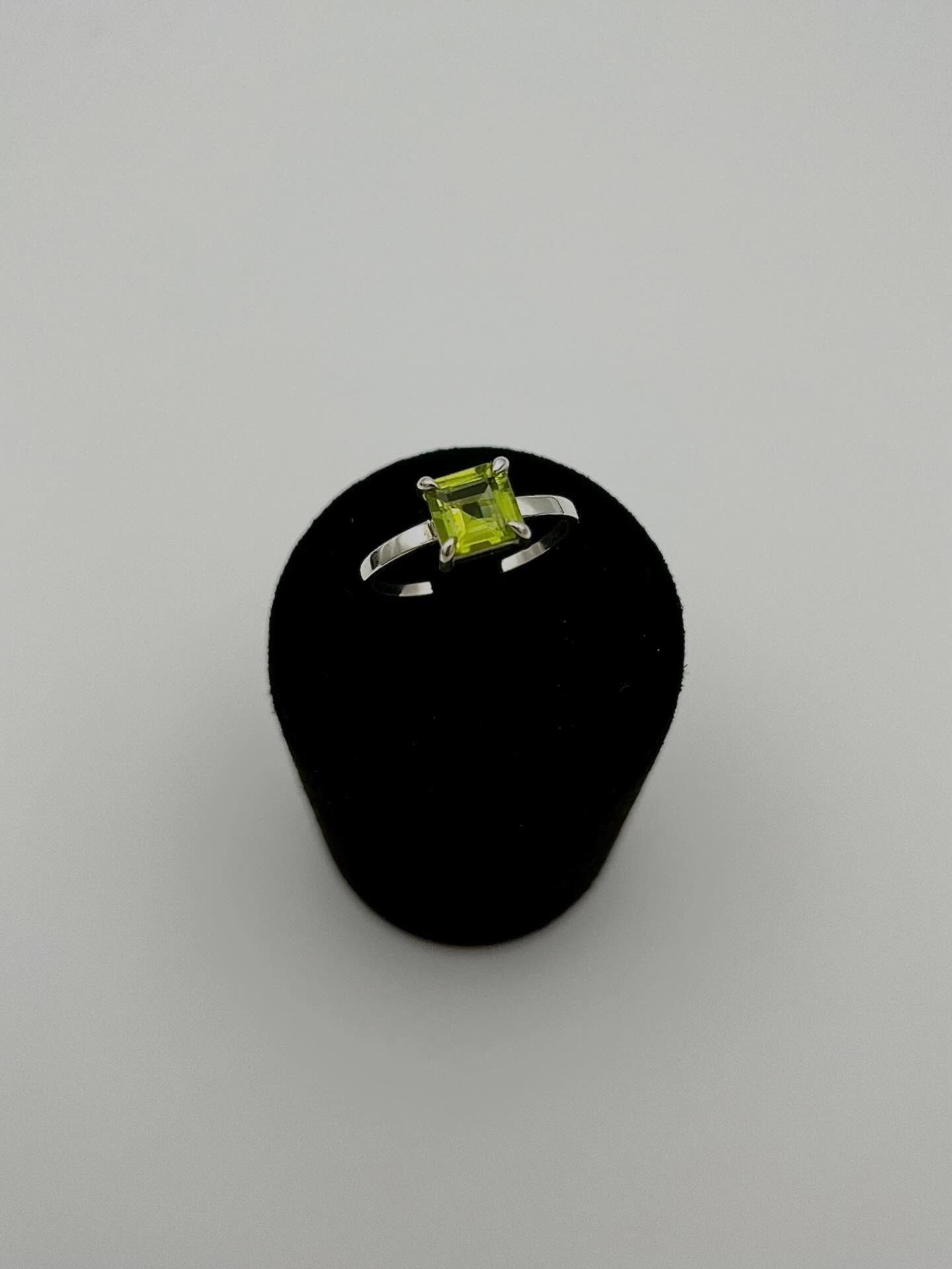 Bague péridot sur monture en argent posée sur un support noir